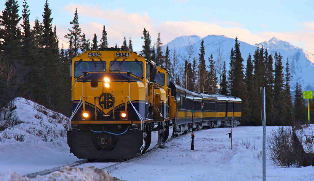 A train is traveling down the tracks in the snow.