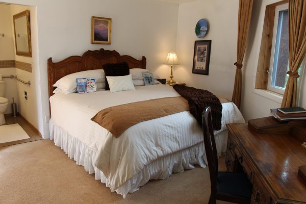 A bed room with a large white bed and brown blanket