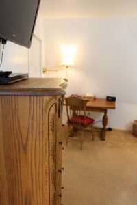 A desk and chair in a room with a television.